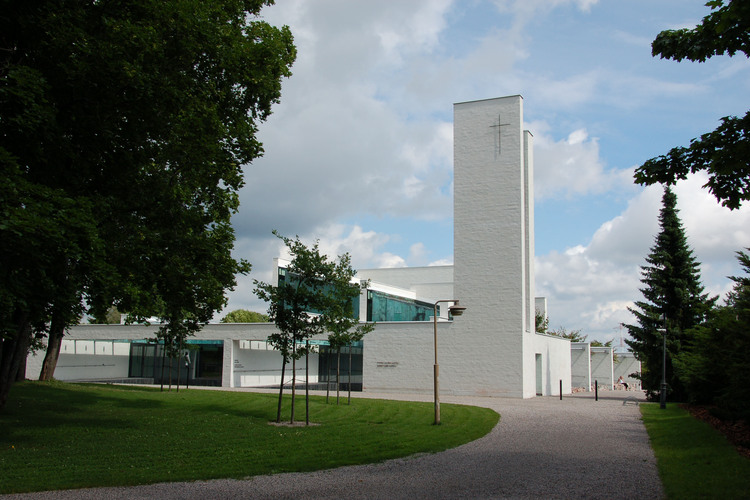 The modern, white stone building of the chapel of St. Lawrence. There are green grass and some trees on the yard.