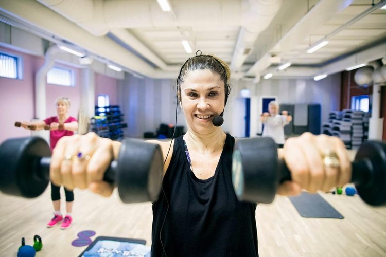 Mariela Salminen nostaa painoja, ryhmän jäsenet tekevät mukana.