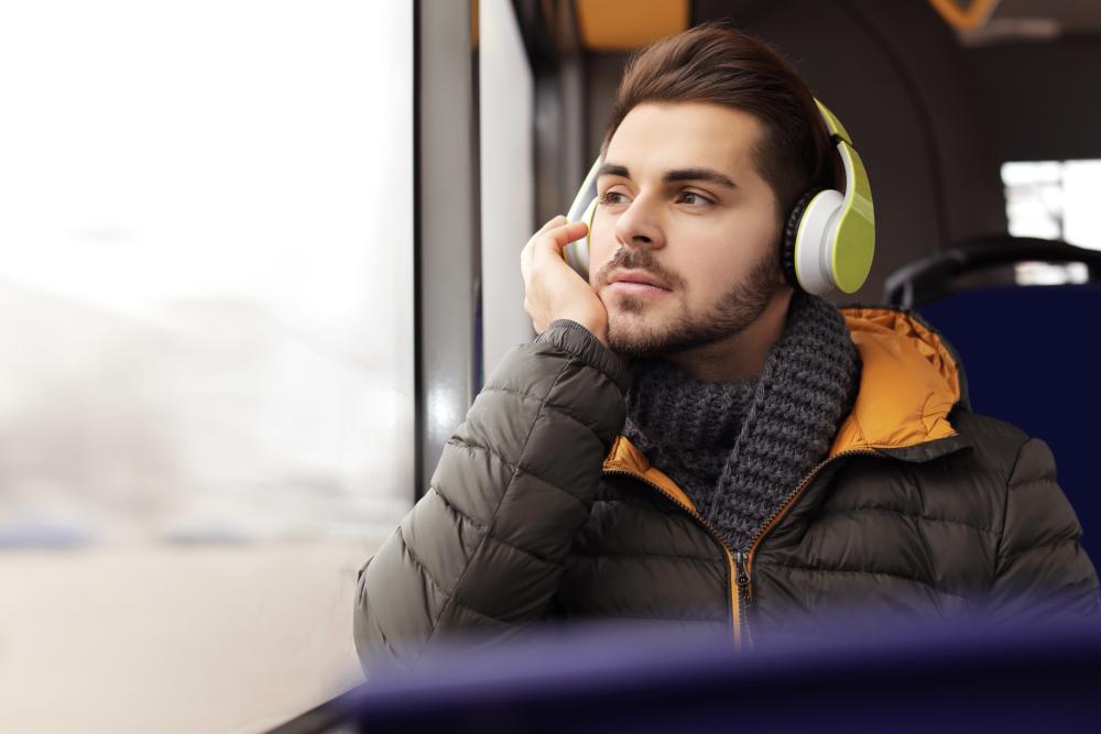 Mies istuu bussissa kuulokkeet päässään. Linkki sivulle, jolla on podcasteja ja musiikkia.
