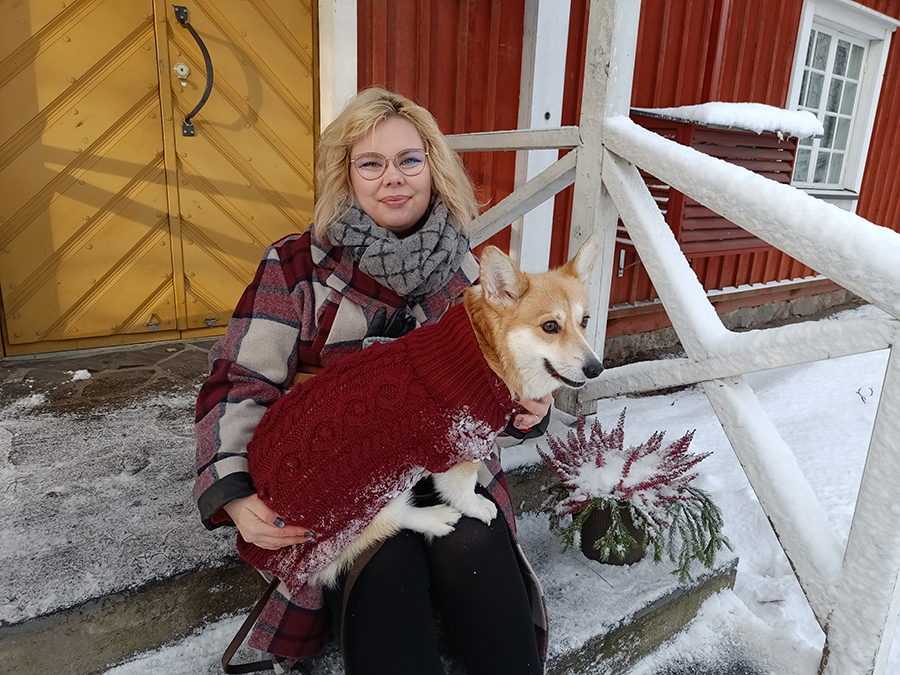 Corgi omistajansa sylissä puutalon portailla.