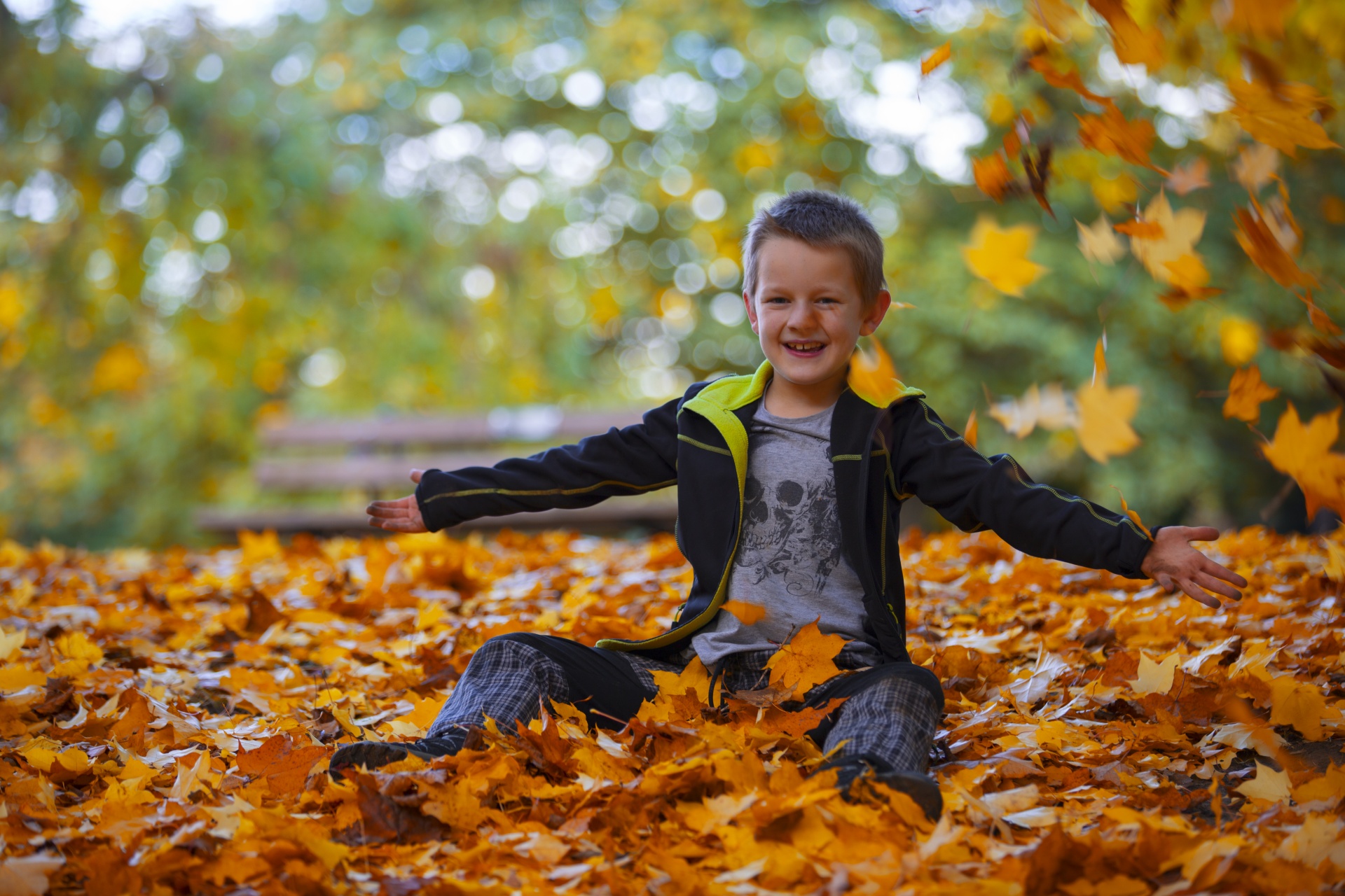 Poika istuu maassa metsässä syksyn lehtien ympäröimänä