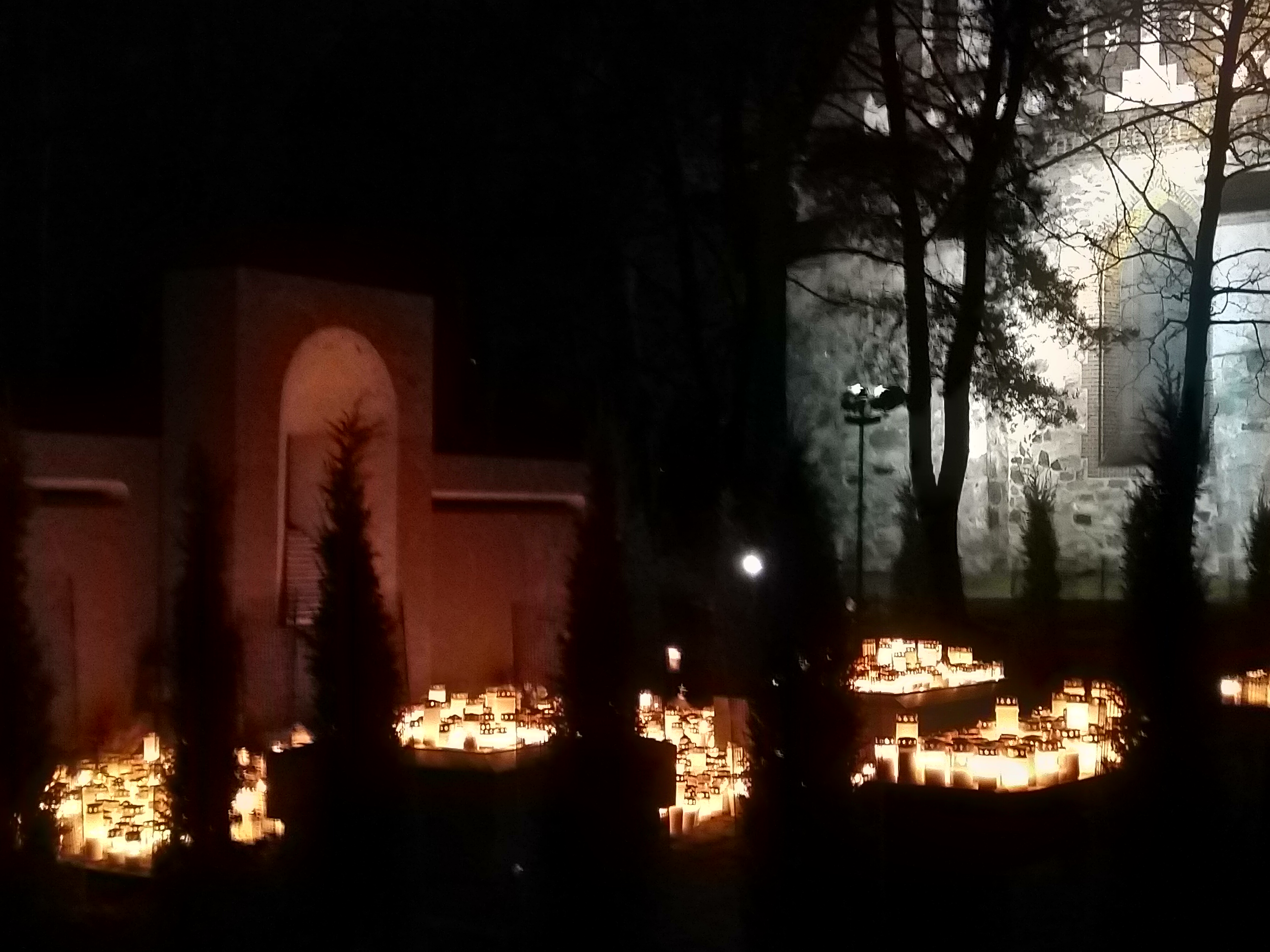 Kirkon seinää ja kynttilämerta pimeässä.