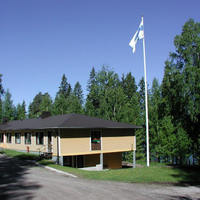 Opiskelijaretriitti Kesijärven leirikeskus kuvassa. Keltatiilinen rakennus, jonka päädyssä seisoo lipputanko jossa on sinivalkoinen Suomen lippu.