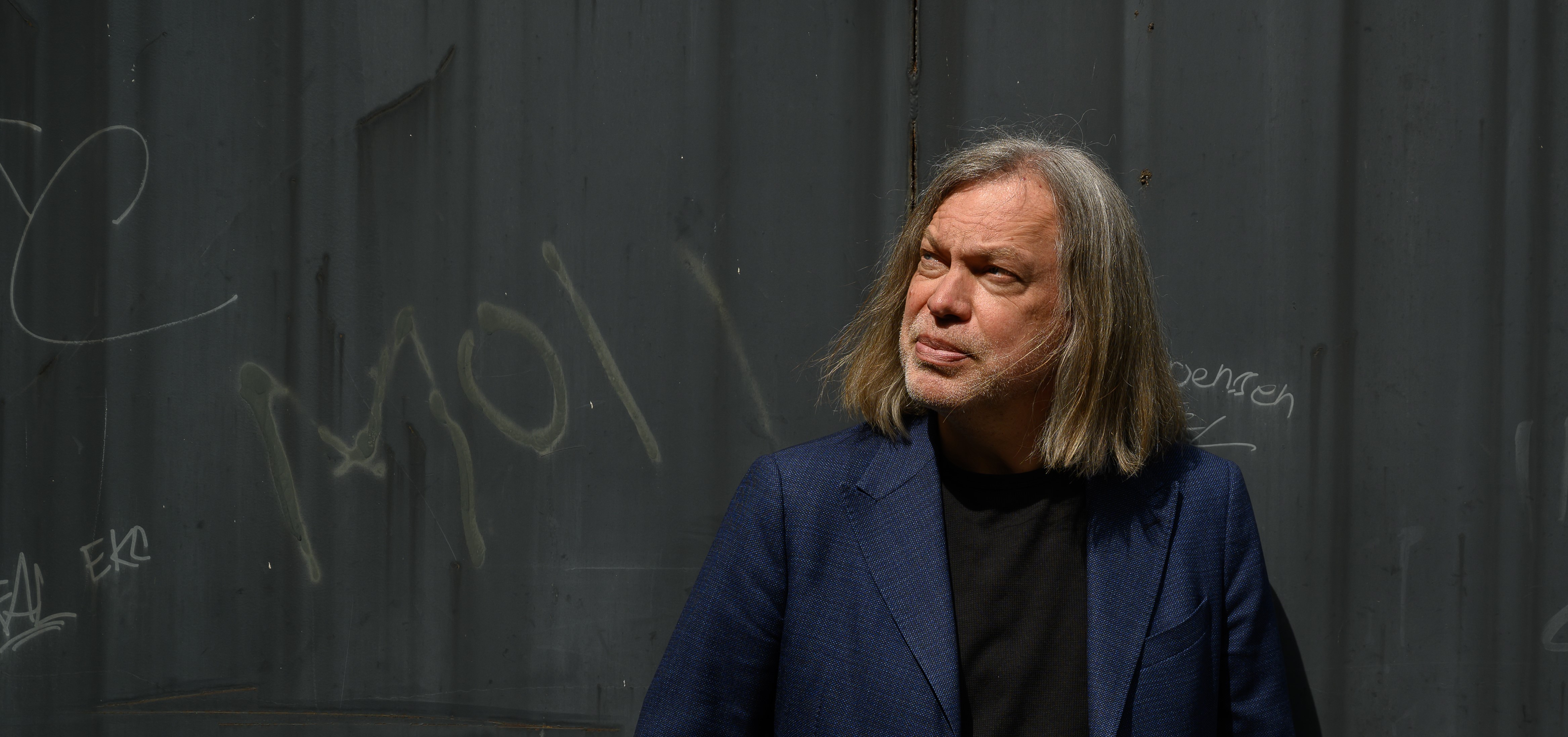 Arto O. Salonen takanaan betoniseinä, jossa lukee moi.
