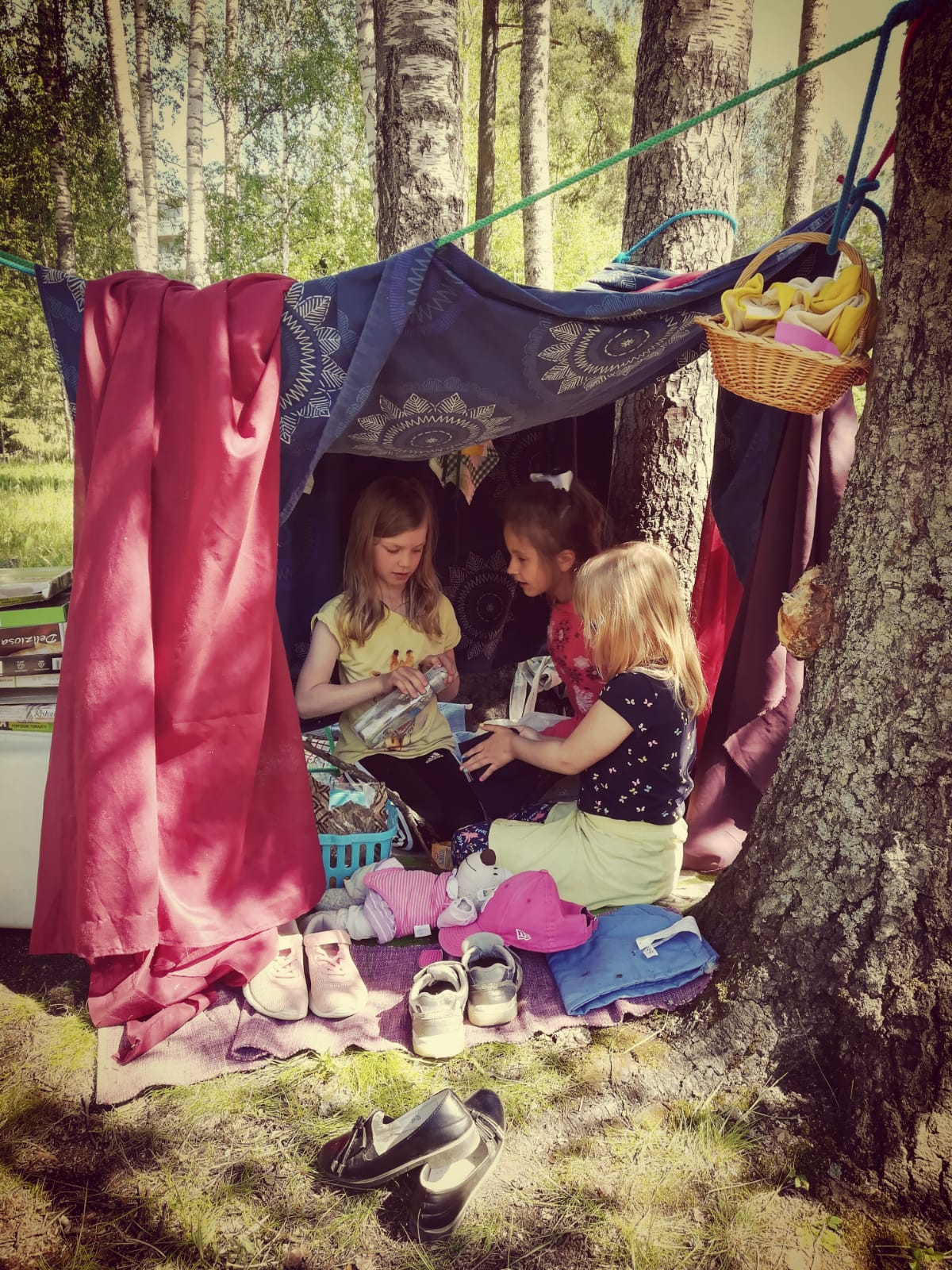 Kesäpäiväleiri koululaisille Tytöt itse tehdyssä majassa ulkona pihalla.
