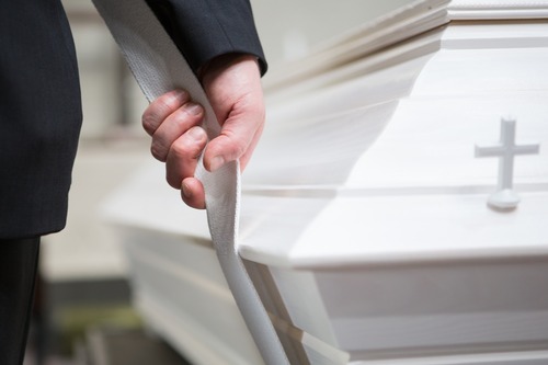 A close-up of a person carrying a coffin.
