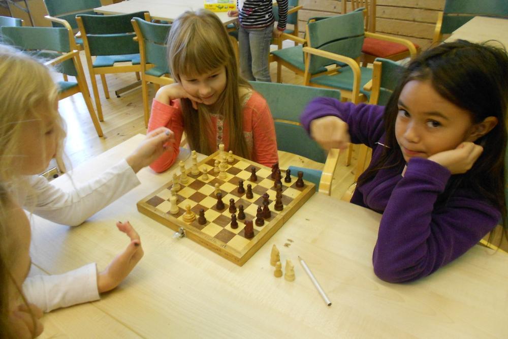 kolme tyttöä pelaavat yhdessä shakkia