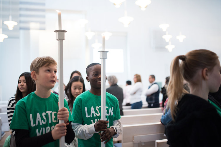 Two children holding tall candles at Mass.