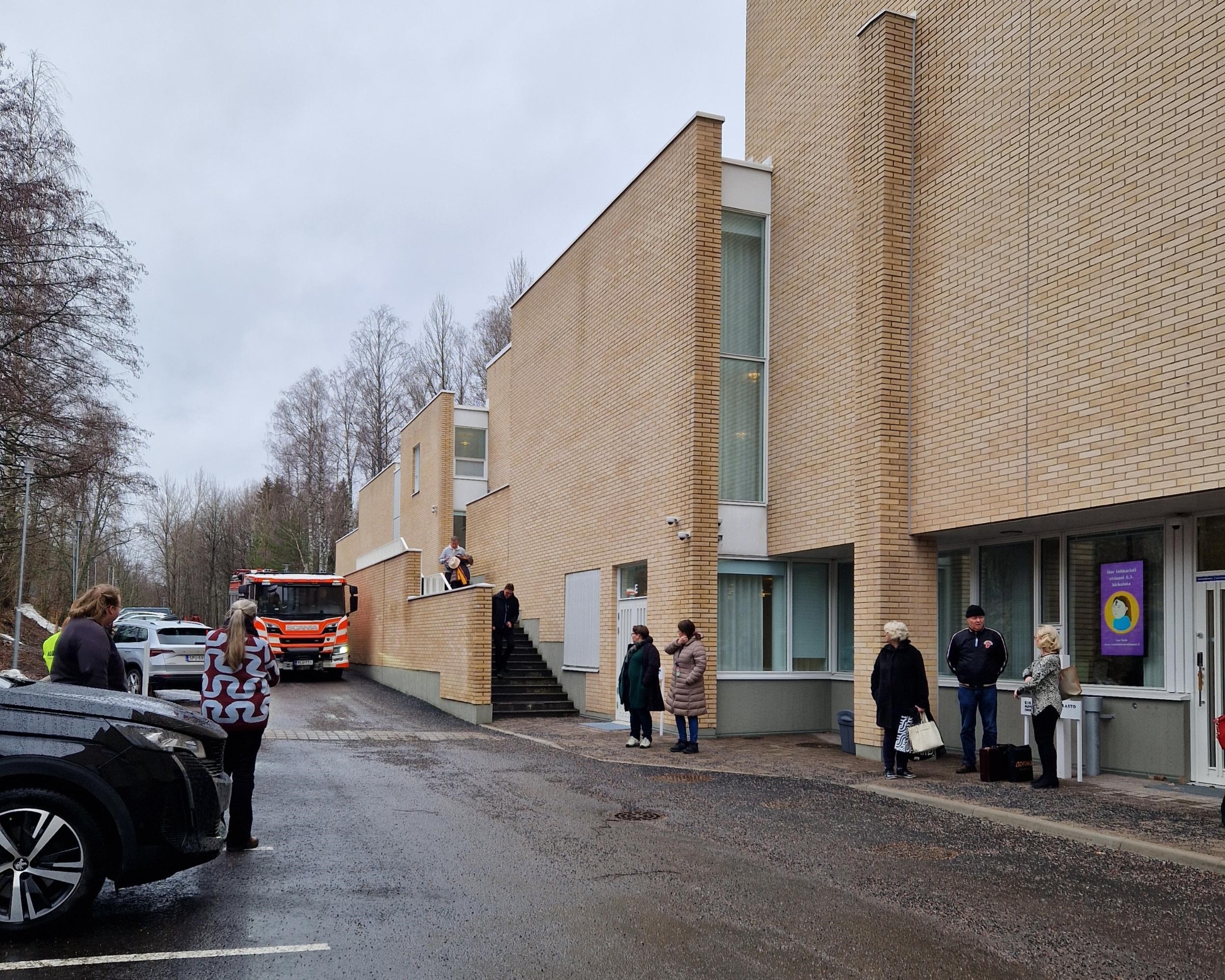 Ihmisiä kirkon pihalla, kun paloauto saapuu.