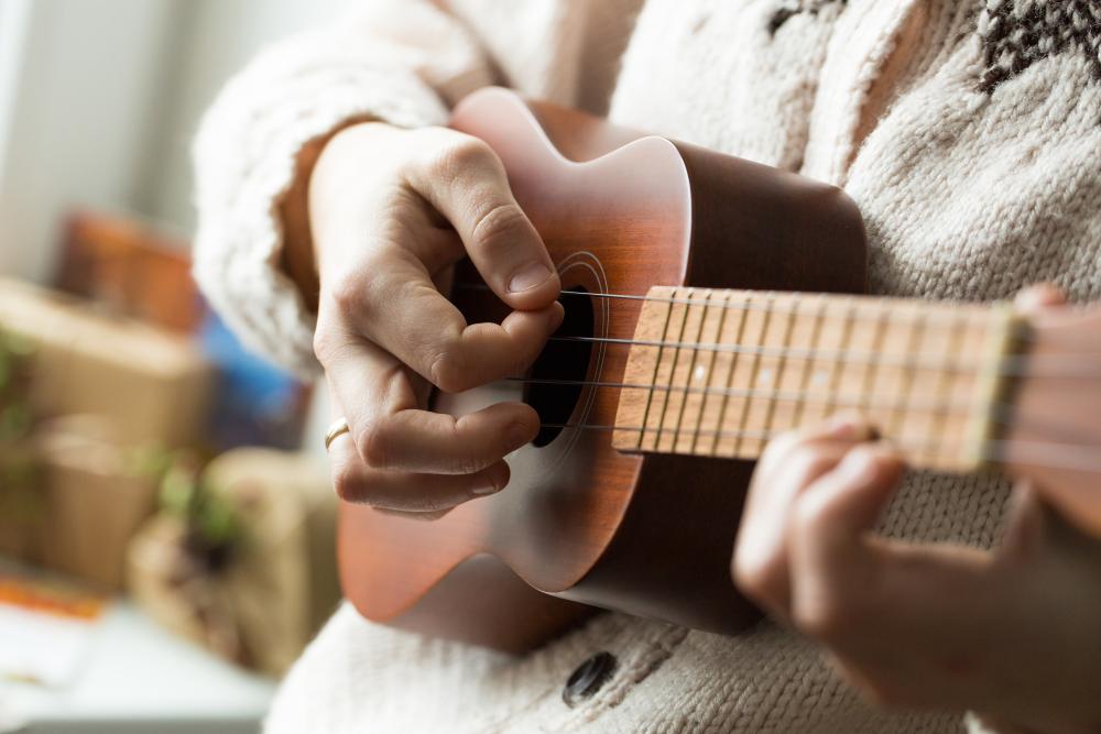Naisen käsi soittaa ukulelea.