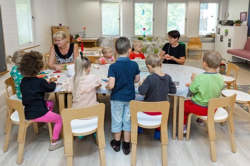 Lapsia ja aikuisia askartelemassa pöydän ääressä
