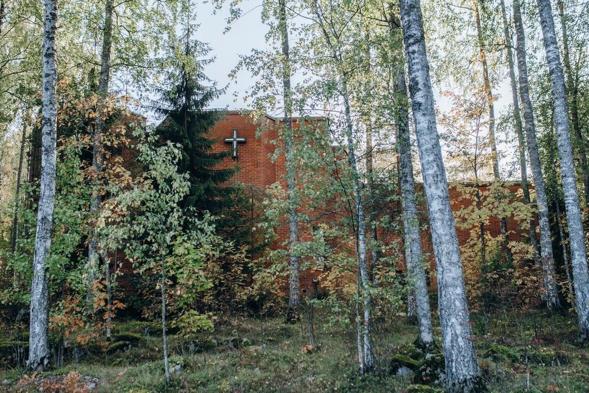 Kivistön punatiilinen kirkko näkyy puiden taustalta.