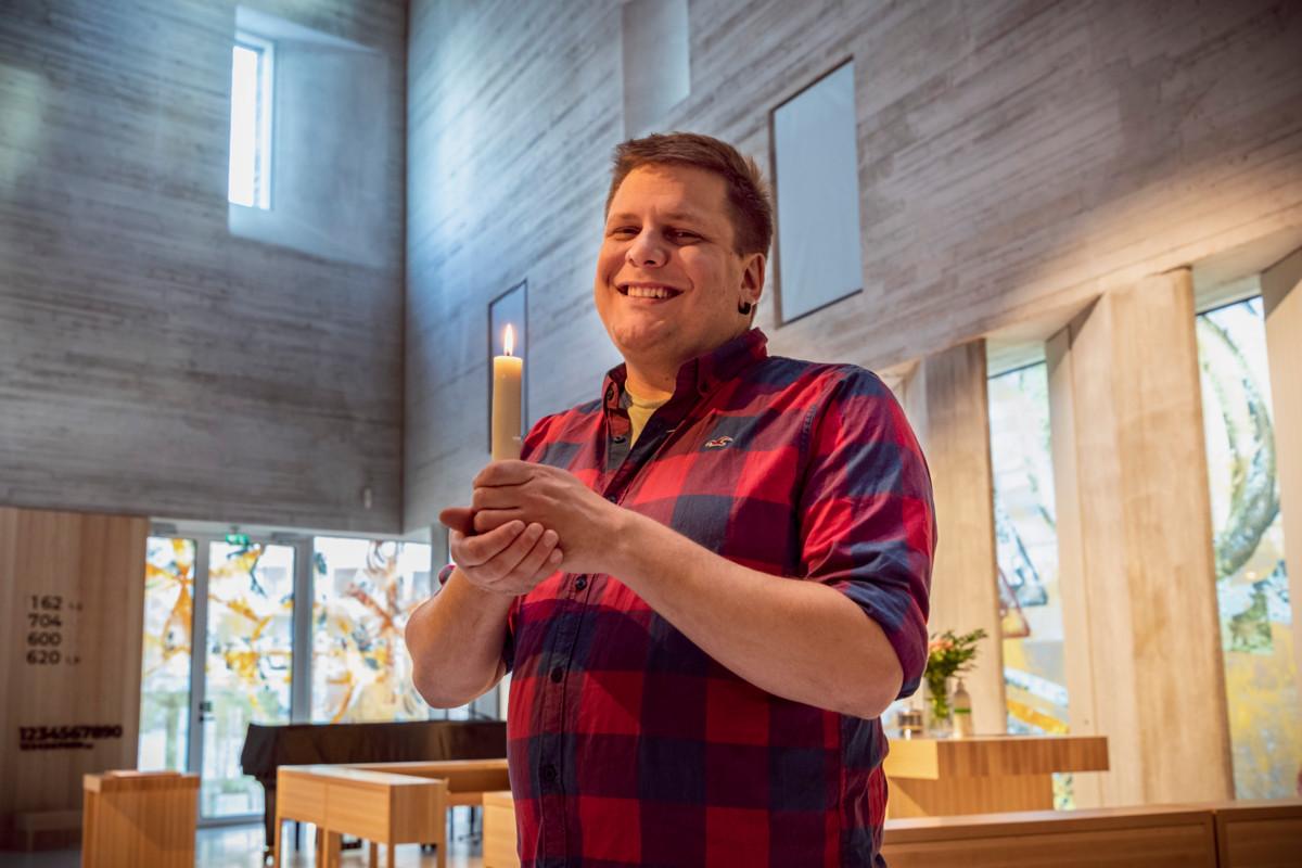 Tikkurilan seurakunnan diakoni Toomas Takala kynttilä kädessä Tikkurilan kirkossa.