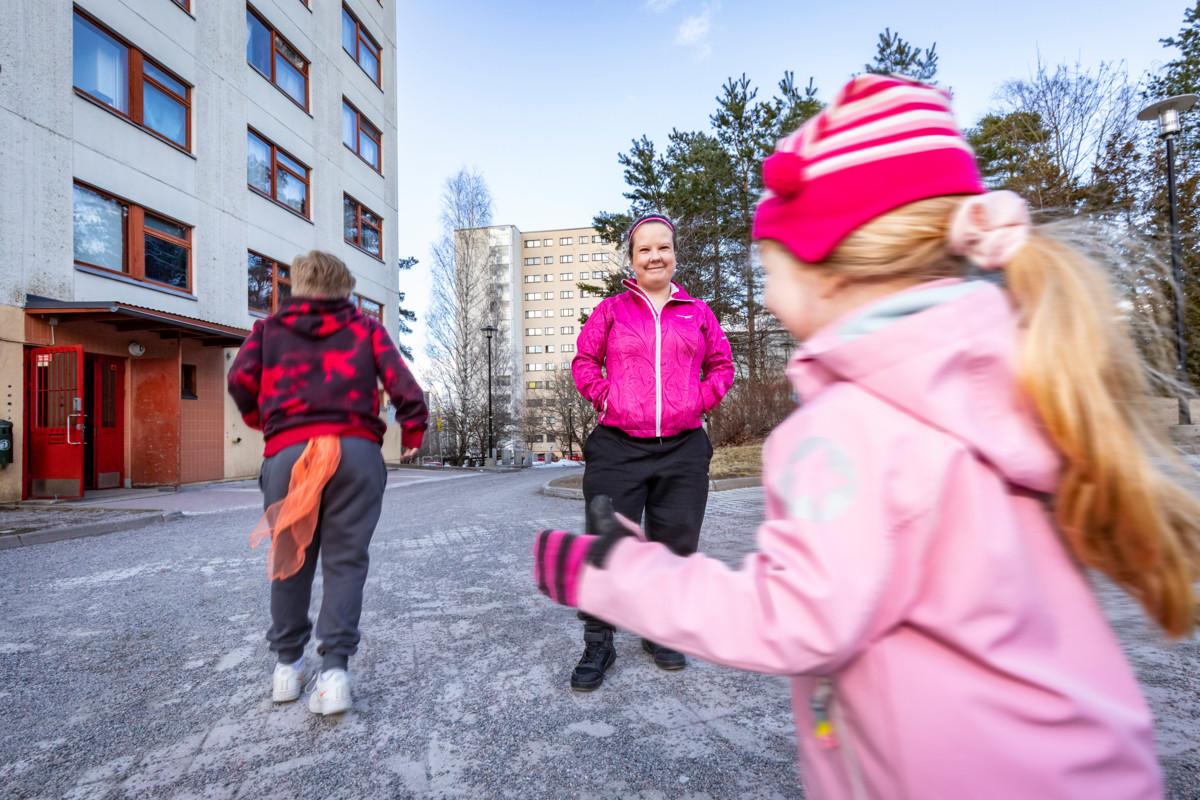 Teija Hietikko ja leikkiviä lapsia kerrostalon pihalla.