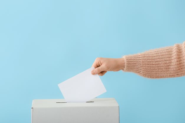Käsi laittaa äänestyslipun vaaliuurnaan