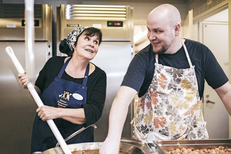 Yhteisen pöydän vapaaehtoiset Irja Stubar ja Niko Tummavuori valmistavat ruokailua Hämeenkylän kirkolla 2017