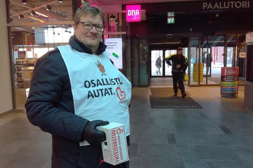 Kirkkoherra Hannu Pöntinen keräyslipas kädessä ja keräysliivi päällä.